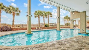 An indoor swimming pool with clear blue water, surrounded by palm trees and lounge chairs. - Bahama Sands Unit PH02 (North Myrtle Beach)