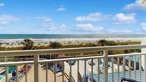 A beachfront view from a balcony with a pool area, lounge chairs, and umbrellas. - Bay Watch Resort 0339 (North Myrtle Beach)