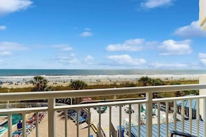 A beachfront view from a balcony with a pool area, lounge chairs, and umbrellas. - Bay Watch Resort 0339 (North Myrtle Beach)