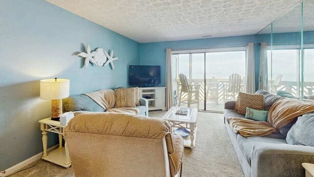 A living room with a sofa, armchair, coffee table, and a television. - Serenity Now Retreat (Murrells Inlet)