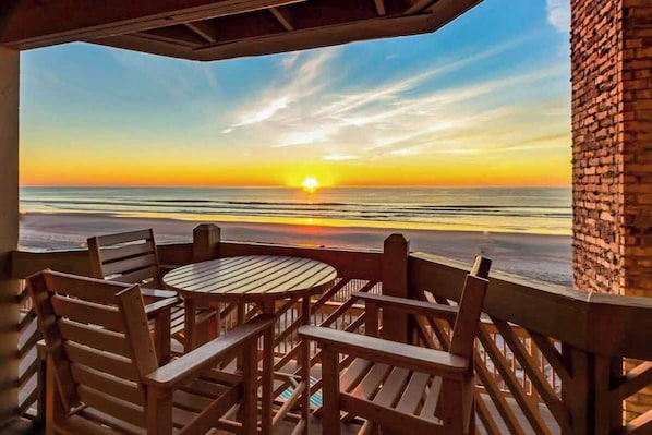 A wooden outdoor seating area with a view of the sunset over the ocean. - Serenity Now Retreat (Murrells Inlet)