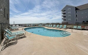 A swimming pool with lounge chairs and a building in the background. - Serenity Now Retreat (Murrells Inlet)