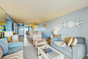 A living room with a light blue sofa, a coffee table, and a dining area in the background. - Serenity Now Retreat (Murrells Inlet)