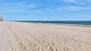 A wide sandy beach with footprints, a clear sky, and a distant shoreline. - Serenity Now Retreat (Murrells Inlet)