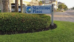 A sign for 'Maritime Place' with a clear view of the surrounding area including a road, parked cars, and residential buildings. - Serenity Now Retreat (Murrells Inlet)