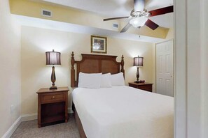 A hotel room with a bed, two bedside tables, a ceiling fan, and a door. - Bahama Sands Unit 0603 (North Myrtle Beach)
