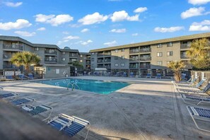 A pool area with lounge chairs, a swimming pool, and multi-story buildings with balconies. - Sea Cabin Unit 137 Condo (North Myrtle Beach)