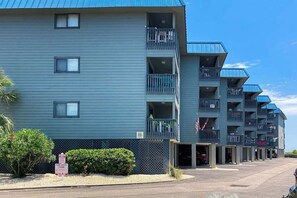 A multi-story hotel with balconies, a parking area, and a 'TON AWAY ZONE' sign. - Sea Cabin Unit 137 Condo (North Myrtle Beach)