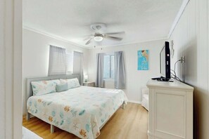 A bedroom with a bed, a ceiling fan, a nightstand, a TV, and a cabinet. - Sea Cabin Unit 137 Condo (North Myrtle Beach)