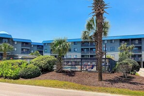 Un hotel con edificios de varios pisos, piscina y zonas ajardinadas con palmeras.