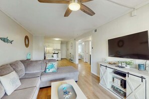 A living room with a grey sofa, a flat-screen TV, and a ceiling fan. - Sea Cabin Unit 137 Condo (North Myrtle Beach)