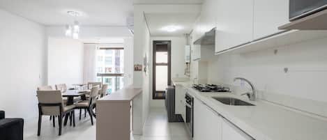 A modern kitchen with white cabinetry, a built-in oven, and a stainless steel sink.