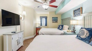 Ein Hotelzimmer mit einem Bett, einem Fernseher, einem Deckenventilator und einem Nachttisch mit einer Lampe.