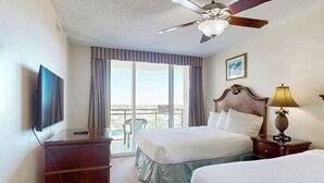 Ein Hotelzimmer mit Bett, Schreibtisch, Fernseher, Lampe und Deckenventilator.