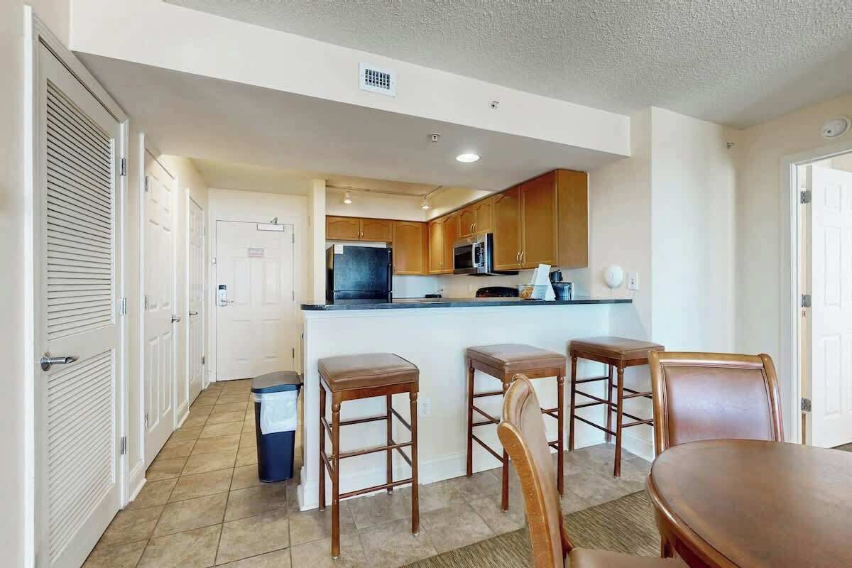 A compact kitchen with wooden cabinets, a microwave, and a small island with stools.