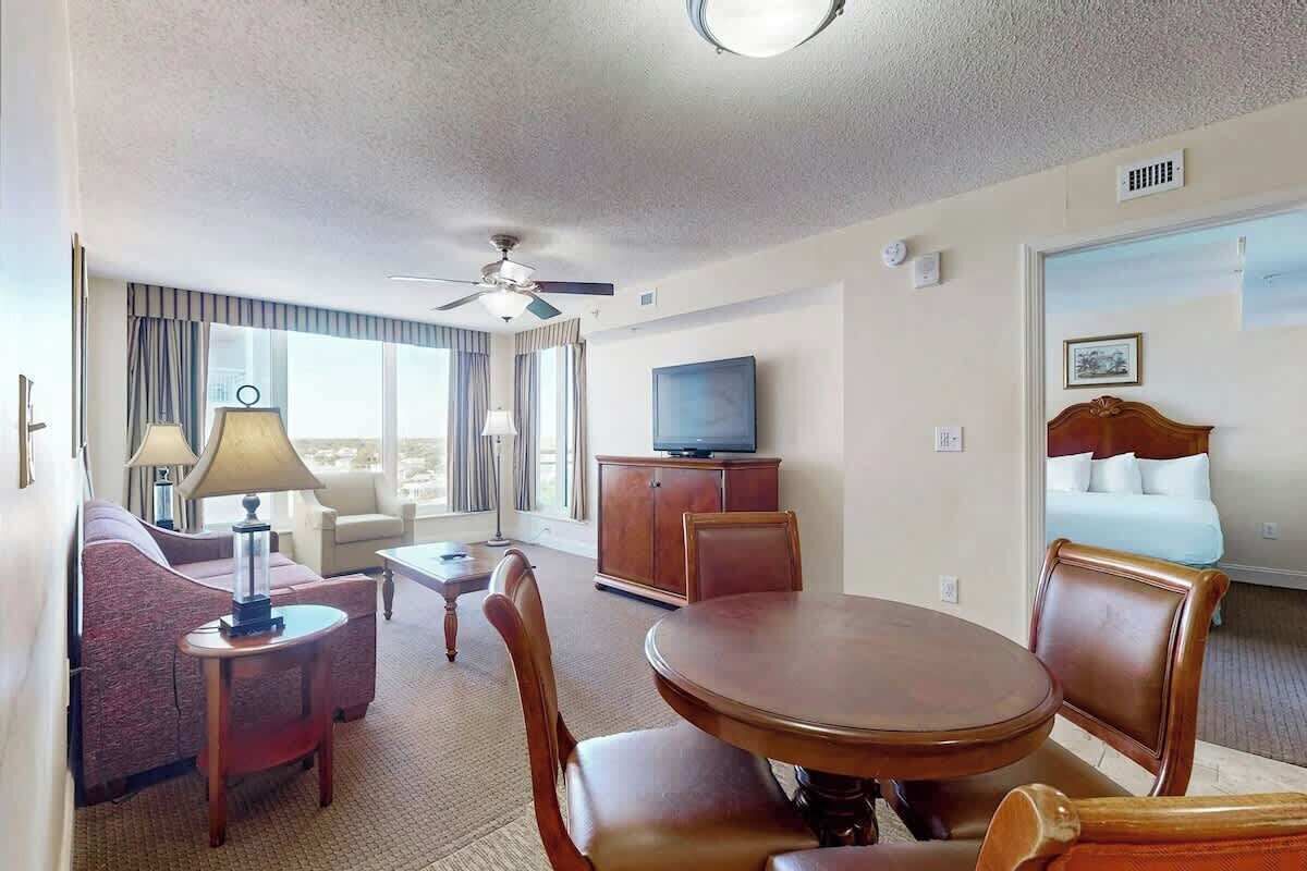 Ein Hotelzimmer mit Essbereich, Fernseher, Bett und einem Fenster mit Vorhängen.
