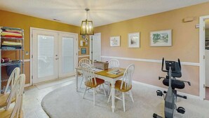 A room with a dining table, chairs, a ceiling fan, a treadmill, and a storage unit with folded clothes. - Willow Winds Unit 17 (North Myrtle Beach)