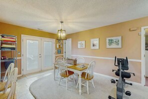 A room with a dining table, chairs, a ceiling fan, a treadmill, and a storage unit with folded clothes. - Willow Winds Unit 17 (North Myrtle Beach)
