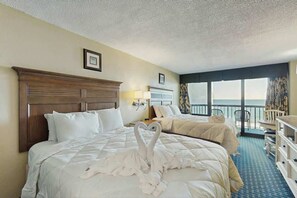 Ein Hotelzimmer mit zwei Betten, einem Balkon und Meerblick.