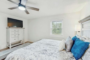 A bedroom with a bed, a ceiling fan, a TV, a window, and a dresser. - Cherry Grove Beach Retreat (North Myrtle Beach)