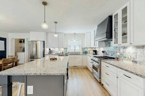 A modern kitchen with granite countertops, stainless steel appliances, and white cabinetry. - Cherry Grove Beach Retreat (North Myrtle Beach)