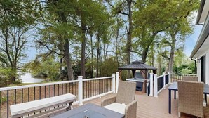 A deck with outdoor furniture, a grill, and a view of a lake. - Cherry Grove Beach Retreat (North Myrtle Beach)