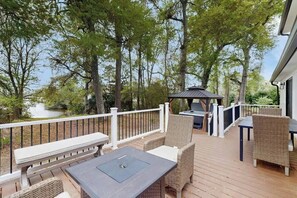 Eine Terrasse mit Gartenmöbeln, einem Grill und Blick auf einen See.