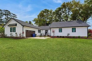 Une maison à deux étages avec un garage, une véranda et une pelouse bien entretenue.