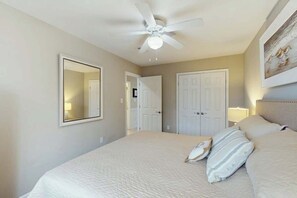 A bedroom with a bed, a ceiling fan, and a door. - Tides Unit C-1 Condo (North Myrtle Beach)
