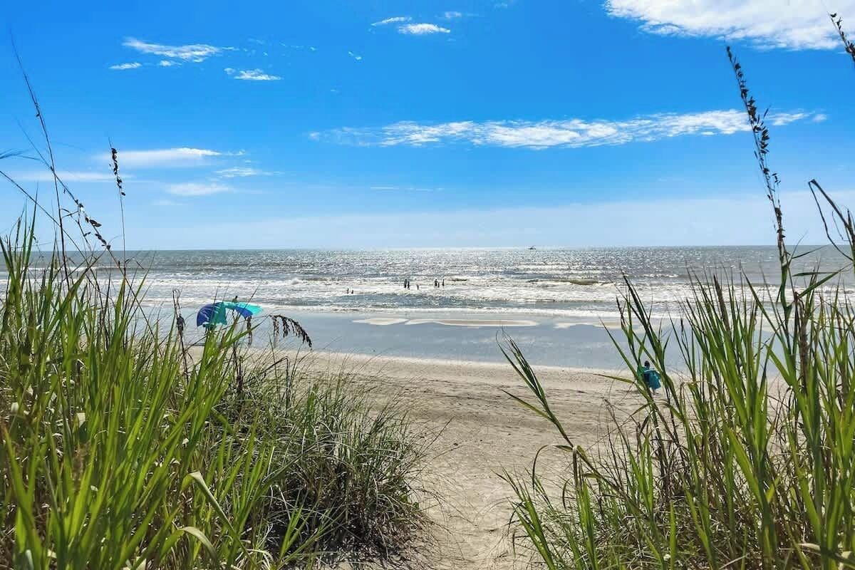 A beach with a clear sky, waves, and people.