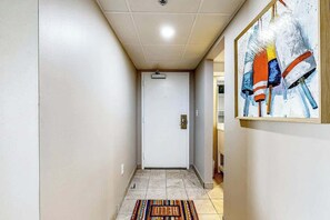 A hallway with a white door, a colorful rug, and a painting on the wall. - Sand Dunes Resort 2647/2648 (Myrtle Beach)