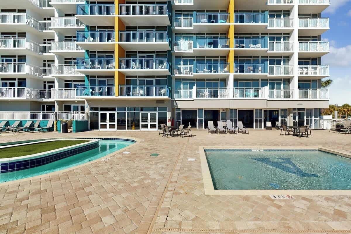 Et hotel med flere balkoner, en swimmingpool og udendørs siddeområder.