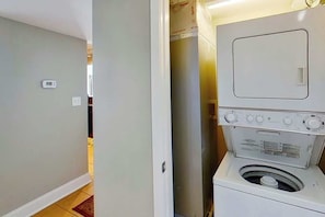 A laundry room with a washing machine and dryer, a thermostat on the wall, and a door leading to another room. - Bahama Sands Unit 0502 (North Myrtle Beach)