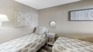 A bedroom with two beds, a bedside table, a mirror, and decorative wall art. - Sands Ocean Club 1629/1630 (Myrtle Beach)