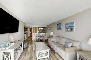 A modern living room with a sofa, a coffee table, and a TV mounted on the wall. - Sands Ocean Club 1629/1630 (Myrtle Beach)