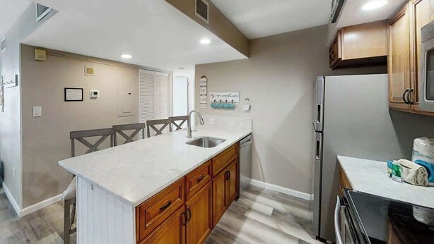 A kitchen with a central island, wooden cabinets, a refrigerator, and a microwave. - Sands Ocean Club 1629/1630 (Myrtle Beach)