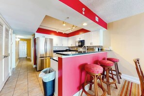 A kitchen with a central island, stainless steel appliances, and a red accent wall. - Bahama Sands Unit 0506 (North Myrtle Beach)