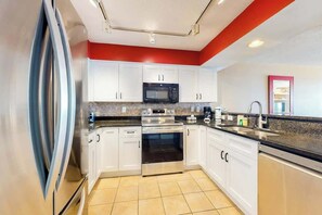 A modern kitchen with white cabinets, stainless steel appliances, and a granite countertop. - Bahama Sands Unit 0506 (North Myrtle Beach)