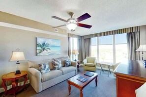 A hotel room with a ceiling fan, a sofa, a chair, a coffee table, and a desk. - Bahama Sands Unit 1201 (North Myrtle Beach)