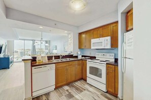 A modern kitchen with wooden cabinets, a built-in microwave, a stove, and a dishwasher. - Harbourgate Unit 0412 (North Myrtle Beach)