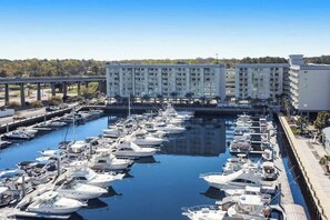 Un port esportiu amb nombroses embarcacions amarrades, un edifici gran de diversos pisos, i un pont al fons.