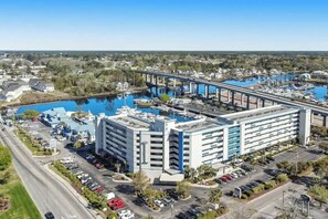 Ein mehrstöckiges Hotel mit Parkplatz und einem Hafen mit Booten.