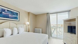 A hotel room with a large bed, a television, a desk, and a window with a view of the city. - Harbourgate Unit 0412 (North Myrtle Beach)