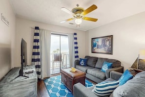 A living room with a ceiling fan, a sofa, a coffee table, and a television. - La Mirage Unit 302 Condo (Myrtle Beach)