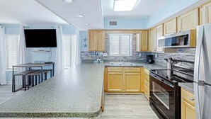 A modern kitchen with granite countertops, wooden cabinets, a built-in oven, and a large window. - Crescent Towers I - 304 (North Myrtle Beach)