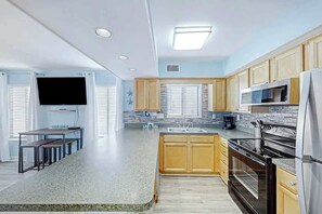 A modern kitchen with granite countertops, wooden cabinets, a built-in oven, and a large window. - Crescent Towers I - 304 (North Myrtle Beach)