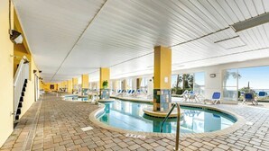 Una piscina interior amb solera de rajoles, gandules i vista despejada cap a l'exterior.