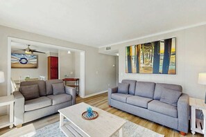 Ein modernes Wohnzimmer mit zwei grauen Sofas, einem Couchtisch und einem Gemälde an der Wand.