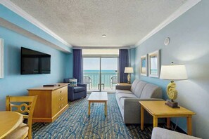 A hotel room with a balcony, a television, a sofa, a desk, and a patterned carpet. - Paradise Resort 1005 (Myrtle Beach)