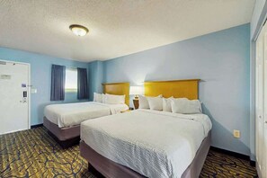 A hotel room with two beds, a wooden headboard, a nightstand, and a patterned carpet. - Paradise Resort 1005 (Myrtle Beach)